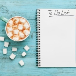 cup of hot cocoa or chocolate with marshmallow and notebook with to do list on turquoise vintage table from above, christmas planning concept. flat lay style.